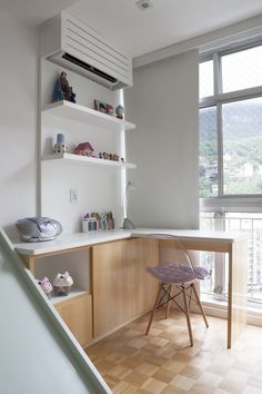 a room with a desk and shelves on the wall, next to a stair case