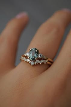 a woman's hand with two rings on it and an aqua blue stone in the middle