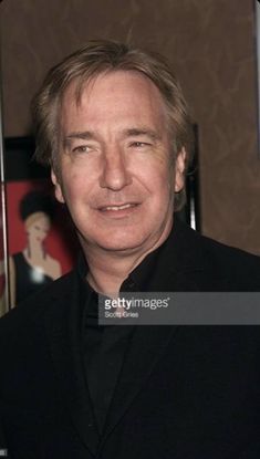 an older man in a black suit posing for the camera