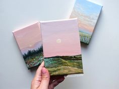 three paintings are being held up in front of each other, one is pink and the other is green