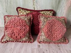 three decorative pillows on a wooden floor