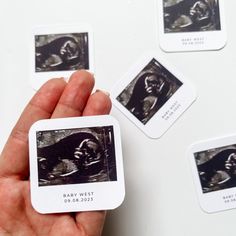 a hand holding a small card with pictures of baby west on it's back