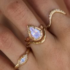 a woman's hand with two rings on it and an opal stone in the middle