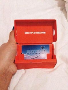 someone is holding an orange box with a credit card in it that says just do it