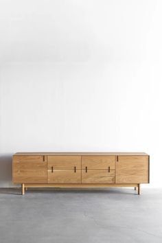 an empty room with a large wooden cabinet on the floor and white wall behind it