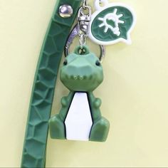 a green alligator keychain is hanging on a wall