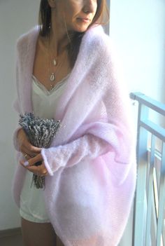 a woman in white shirt and pink cardigan holding flowers