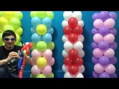 a man is sitting in front of balloons and holding an object with one hand while the other