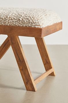 a wooden bench with a white cushion sitting on it's backrest and legs