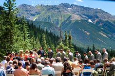 a group of people that are standing in front of some trees and mountains with flowers