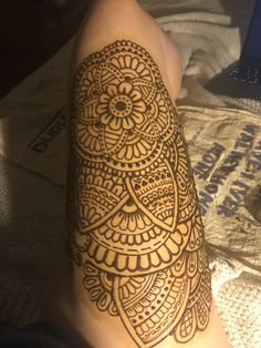 a person with a henna tattoo on their arm and leg, showing the intricate design