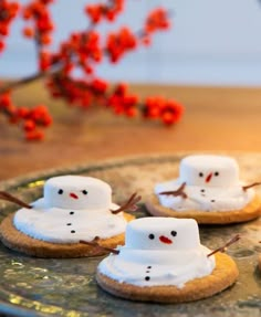 cookies decorated with marshmallows and snowmen on a platter next to red berries