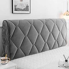 the headboard of a bed is upholstered with grey fabric and tassels