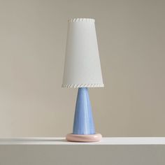 a blue table lamp sitting on top of a white shelf next to a light gray wall