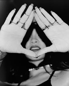 black and white photograph of a woman making a heart with her hands in front of her face