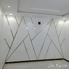 an empty room with white walls and gold lines on the wall