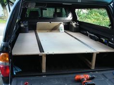 the back end of a truck with a table in the trunk and tools on the floor