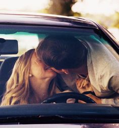 a man and woman kissing in the back seat of a car