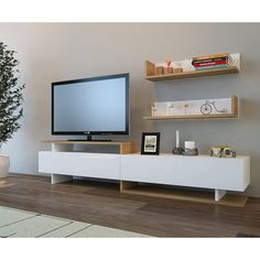 a flat screen tv sitting on top of a white entertainment center next to a potted plant