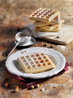 two waffles on a plate with some nuts next to them