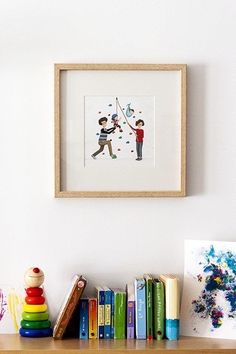 children's artwork hangs on the wall above a bookshelf