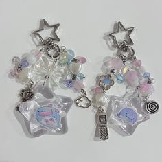 two charms are attached to each other on a white surface with silver stars and beads