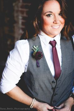 a woman wearing a vest and tie with a flower in her lapel