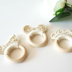 three pieces of ivory colored wood with crochet designs on them and a white rose