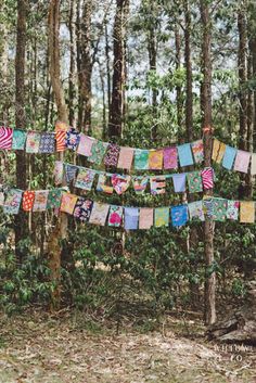 the flags are hanging from the trees in the woods, with colorful designs on them