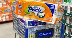 a shopping cart filled with toilet paper and cleaning wipes in a grocery store aisle