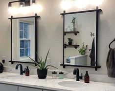 a bathroom with two sinks, mirrors and lights on the wall above them is shown