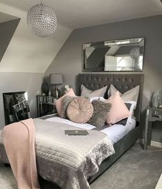 a bedroom with grey walls and pink pillows on the bed, along with two mirrors