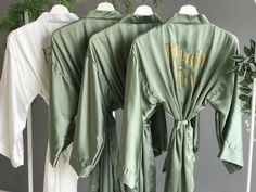 Satin Bridesmaid robes/Bridal robe. Luxurious bride kimono robe in olive sage for Mother of the Bride/Groom. Personalized Womens clothing. Our bridesmaid robes and bridal robe collection features the perfect bride robe for your special day. These elegant kimono robes are made from luxurious satin and come in stunning shades like sage, olive and more. With long, ankle-calf length option, our personalized robes add a unique touch for everyone, including the Mother of the Bride. Ideal for bridesmaid proposals, bachelorette parties, and as getting ready outfits, these robes are a must-have in women's clothing for any bridal celebration. PROCESS: If you choose the robes with text option, put the names/text/roles etc in the personalization box at the time of checkout. Please mention your preferr Green Long Sleeve Bridesmaid Gown, Bridesmaid Robe Pictures Sage Green, Green Long Sleeve Wedding Robe, Bridal Party Robes Sage Green, Sage Bridesmaid Robe, Bridesmaids Robe Sage Green, Elegant Green Silk Robe, Bride Kimono, Elegant Kimono