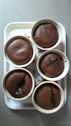 four chocolate cupcakes sitting on top of a white plate