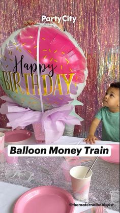 a baby sitting in front of a balloon with the words happy birthday balloon money train