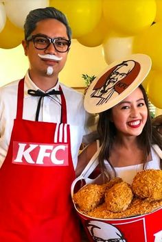 a man and woman standing next to each other in front of some balloons with kfc's logo on them