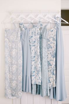 four dresses hanging on a rack in front of a door with hangers holding them