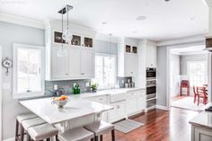 a large kitchen with white cabinets and wood flooring, along with an island in the middle