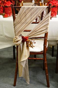 a chair with a bow tied to it sitting in front of a table full of flowers