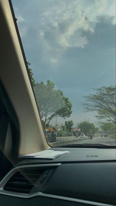 the view from inside a car looking at trees and cars driving down the road in front of them