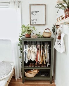 a green cabinet filled with lots of clothes next to a potted houseplant