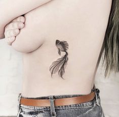 a goldfish tattoo on the back of a woman's stomach