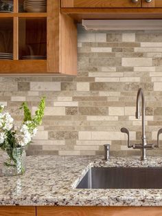 a kitchen counter with a sink and some flowers in a vase next to the faucet