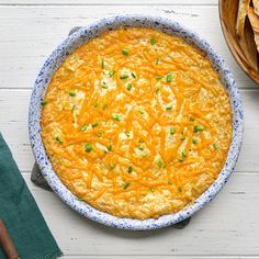 a blue and white dish filled with food next to tortilla chips on a table