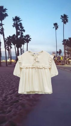 a white shirt hanging on the side of a road next to palm trees and buildings