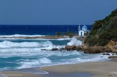 waves crashing on the beach with a church in the background