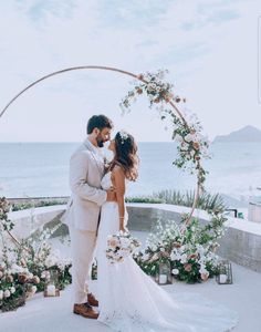 a bride and groom standing under an arch with flowers