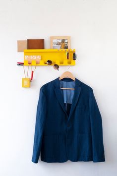 a blue jacket hanging on a wall next to a yellow shelf