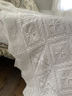 a white crocheted blanket sitting on top of a bed next to a window