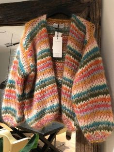 a multicolored sweater hanging on a clothes rack in front of a wooden frame